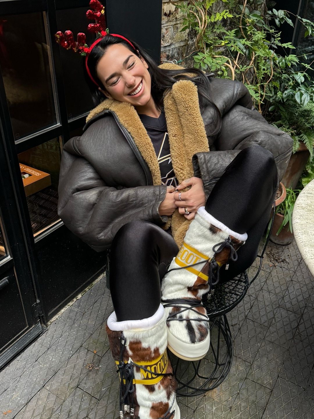 Dua Lipa poses for a photo in cowhide moon boots and a leather jacket