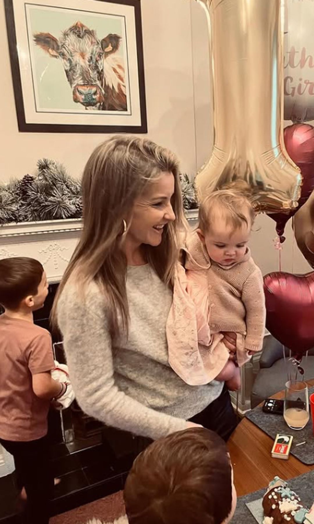 Helen Skelton holding a baby girl in front of a table with party food