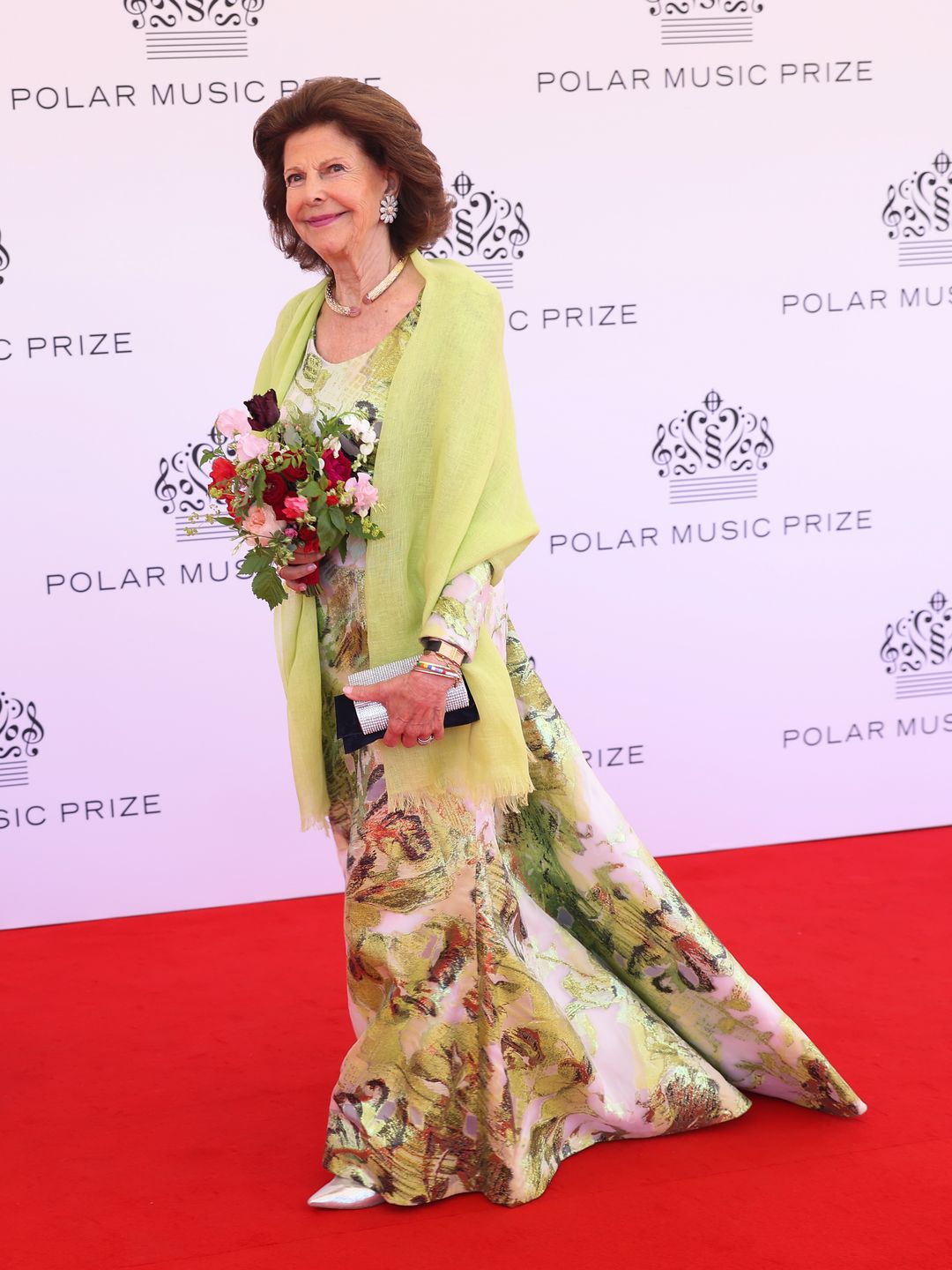 Full body picture of Queen Silvia in a yellow and floral dress