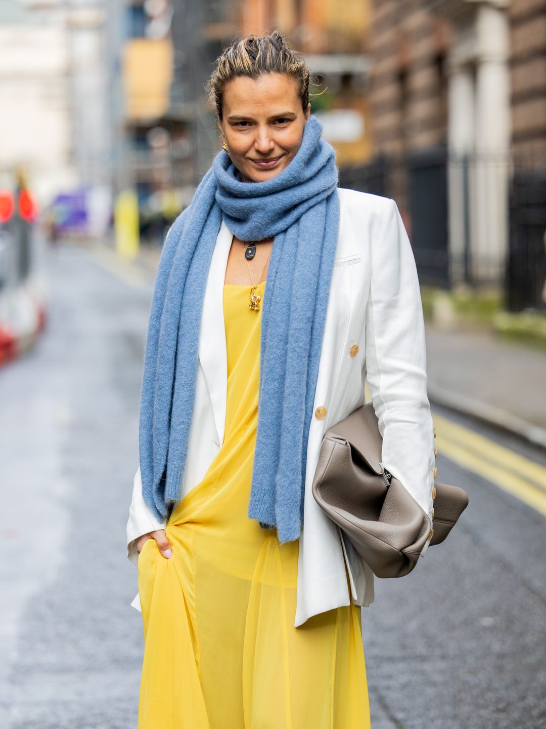 Mija Knezevic wears yellow dress, blue scarf, white blazer, brown bag outside Eudon Choi during London Fashion Week 