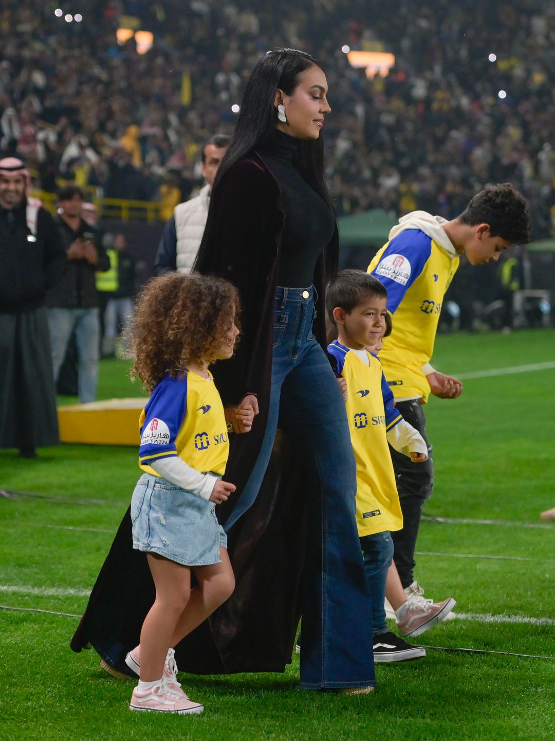 Georgina Rodriguez, wife of Cristiano Ronaldo walks out with her children during the official unveiling of Cristiano Ronaldo as an Al Nassr player at Mrsool Park Stadium in a pair of blue jeans and a black turtleneck 