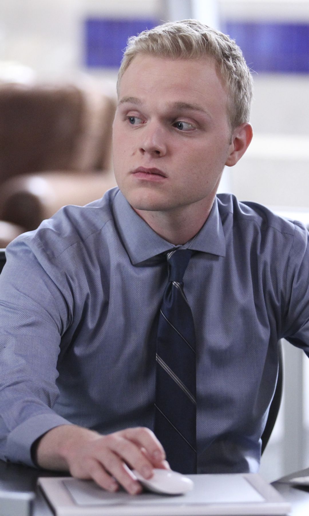 Still image of Joe Adler as Jason Wyle in The Mentalist; he sits at a desk in a blue shirt and tie