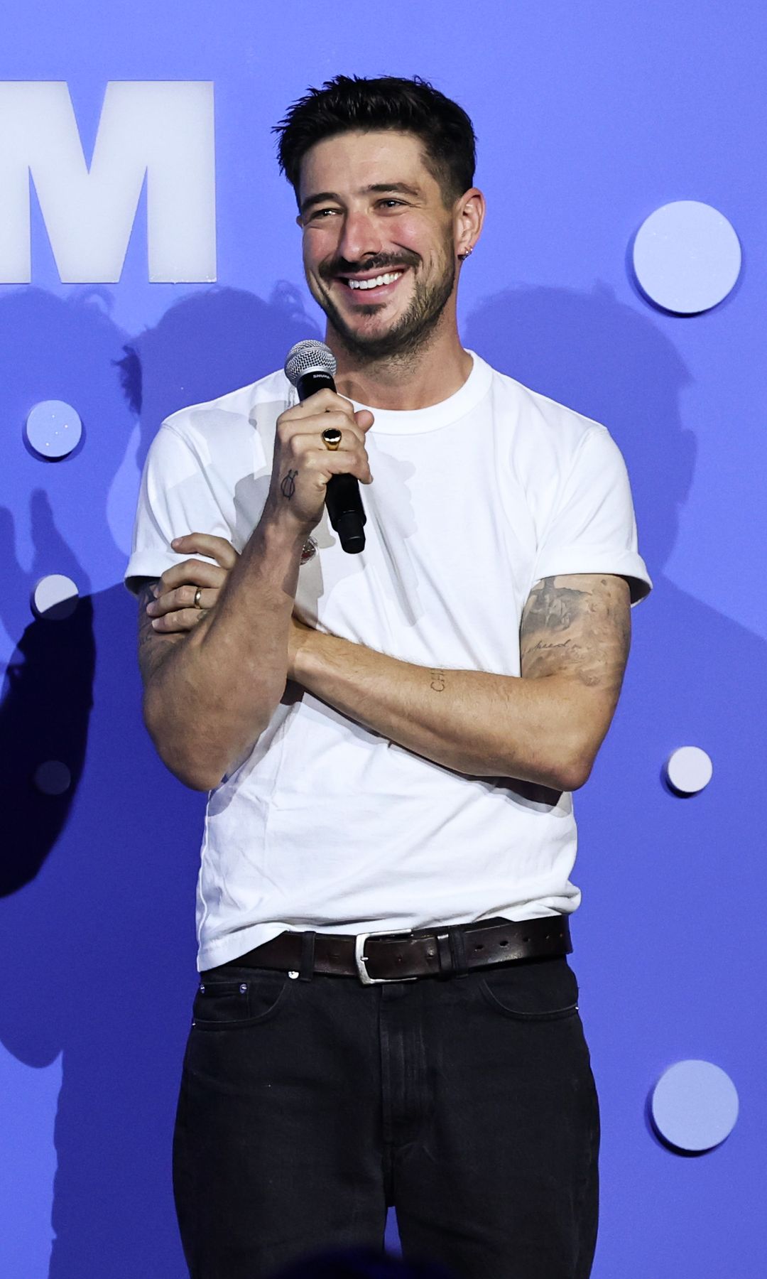 Marcus Mumford dans un t-shirt blanc tenant un microphone