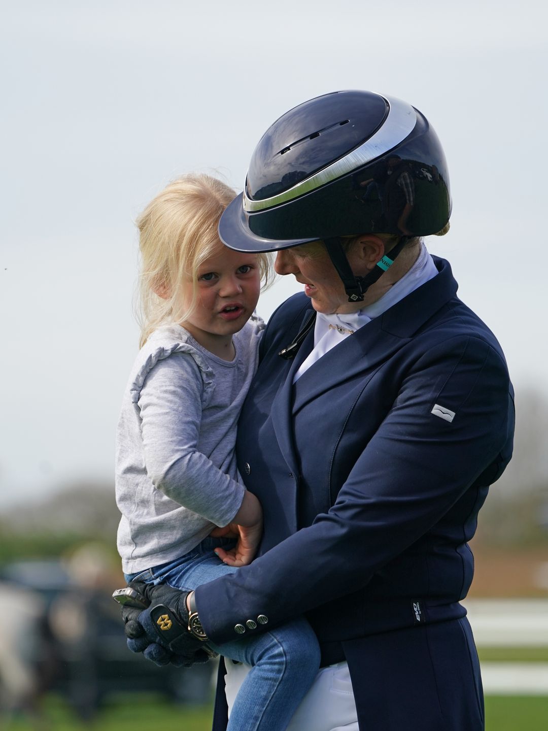 woman holding young girl at equestrian event 