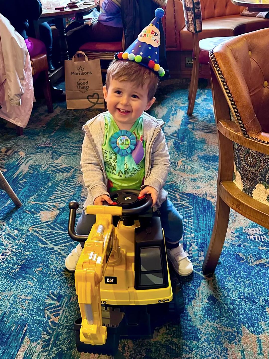 young boy sitting on yellow digger toy 