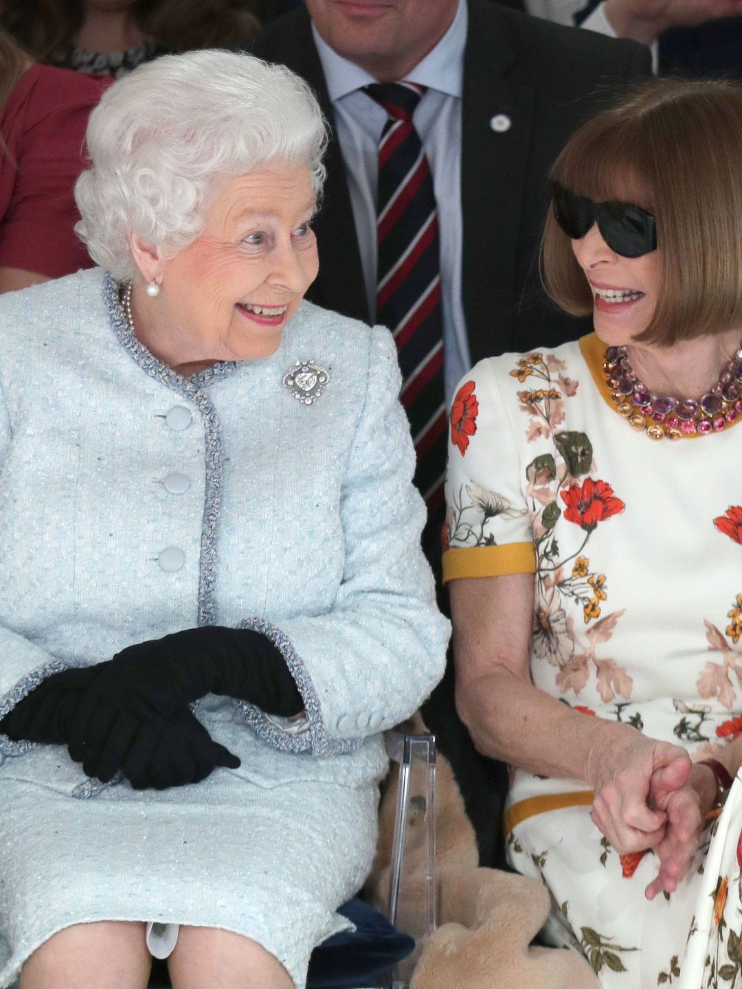 Queen Elizabeth and Anna Wintour smile as they sit front row at Richard Quinn's runway show in London.