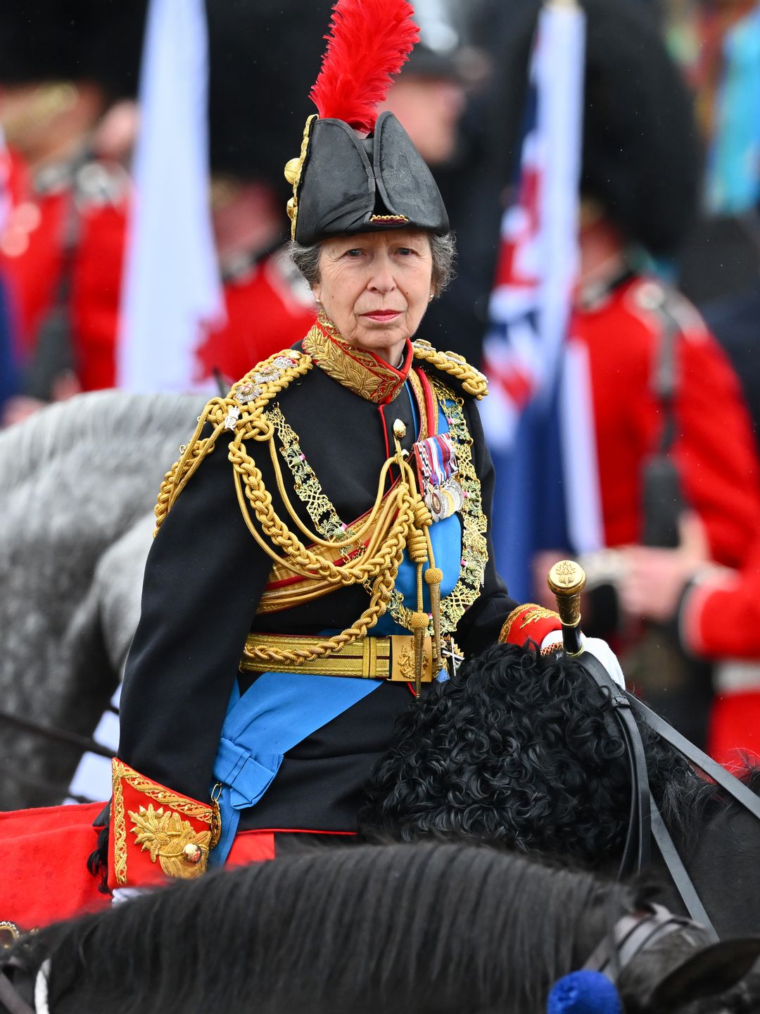 Princess Anne rides on horseback behind the gold state coach