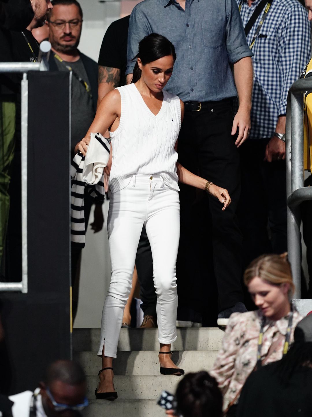 Meghan Markle in a white cable knit sweater vest and skinny jeans 