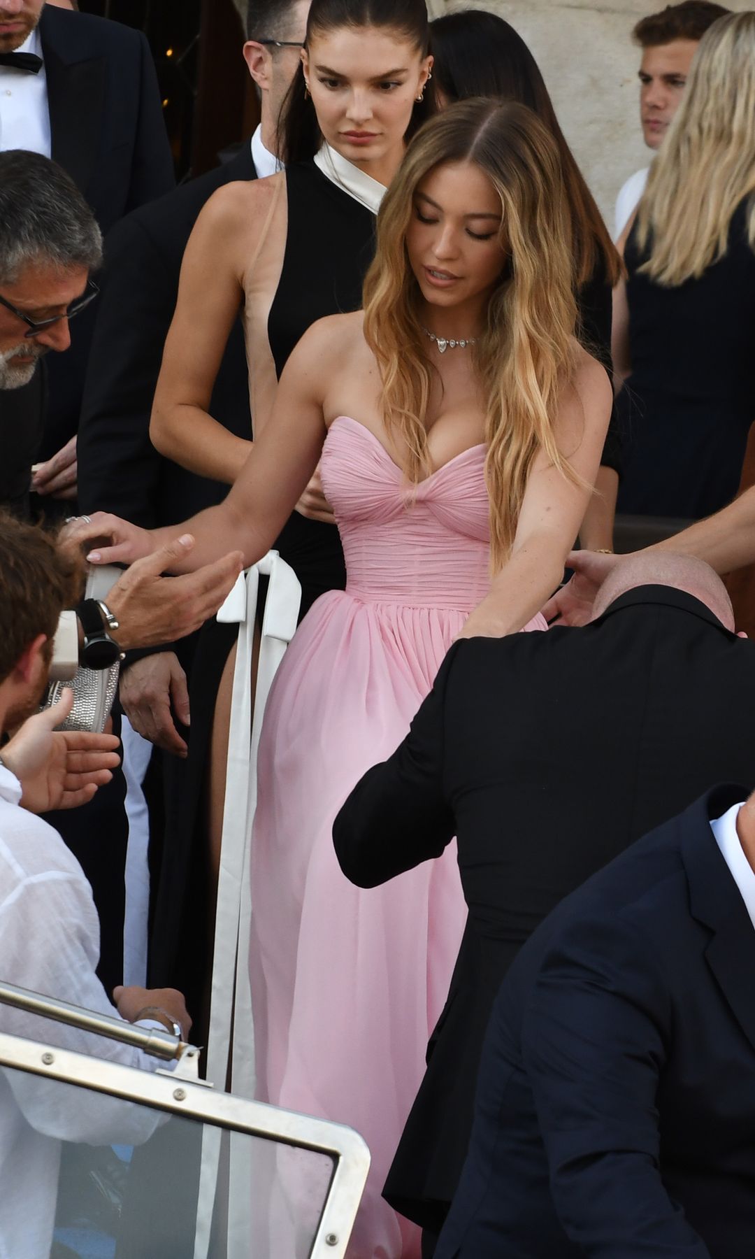 Sydney Sweeney wore a strapless pink gown with a corseted bodice and diamond necklace as she arrived by boat at the Bezos wedding