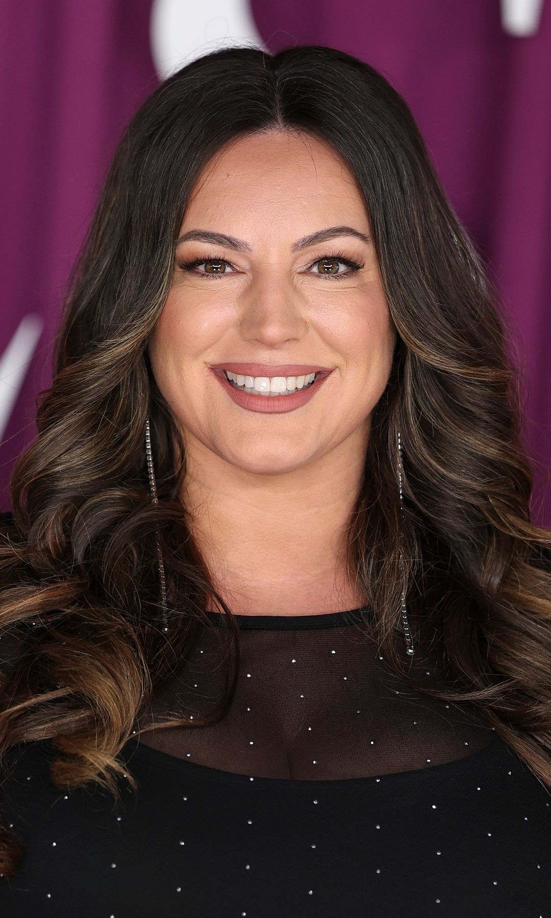 Kelly Brook smiling in a black dress