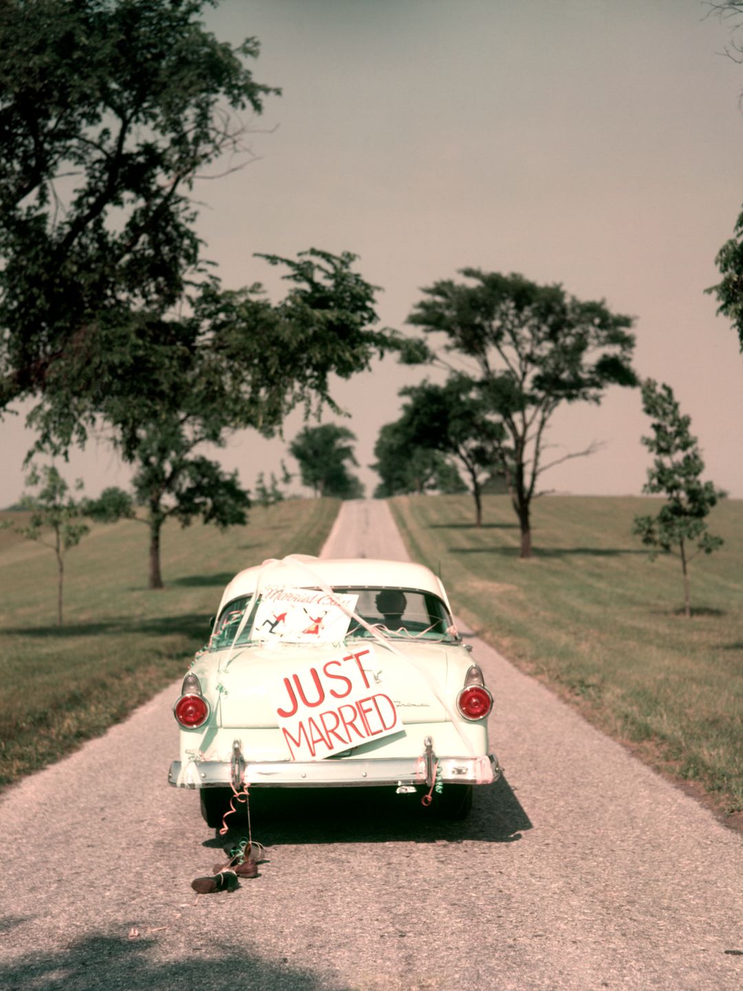 1950s COUPLE BRIDE AND GROOM RIDING IN FORD SEDAN ON BEGINNING OF LONG ROAD JUST MARRIED SIGN AMERICANA NOSTALGIA  (Photo by H. Armstrong Roberts/ClassicStock/Getty Images)