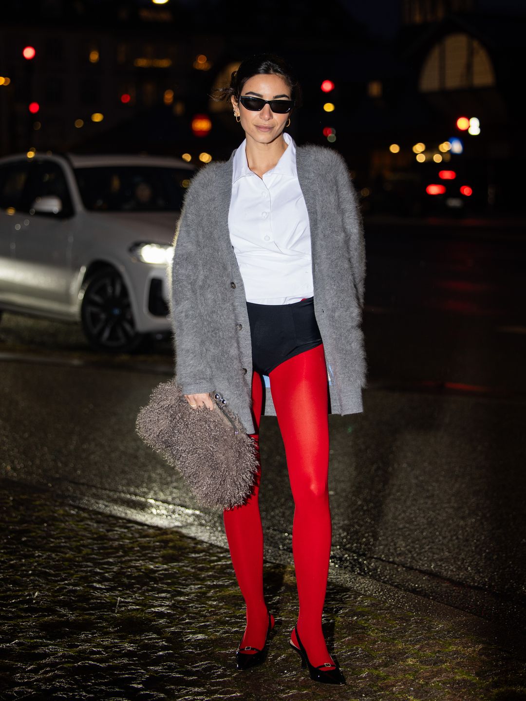 Mariona Autran wears  grey cardigan, blazer, micro shorts, red tights, heels, bag outside Remain during the Copenhagen Fashion Week