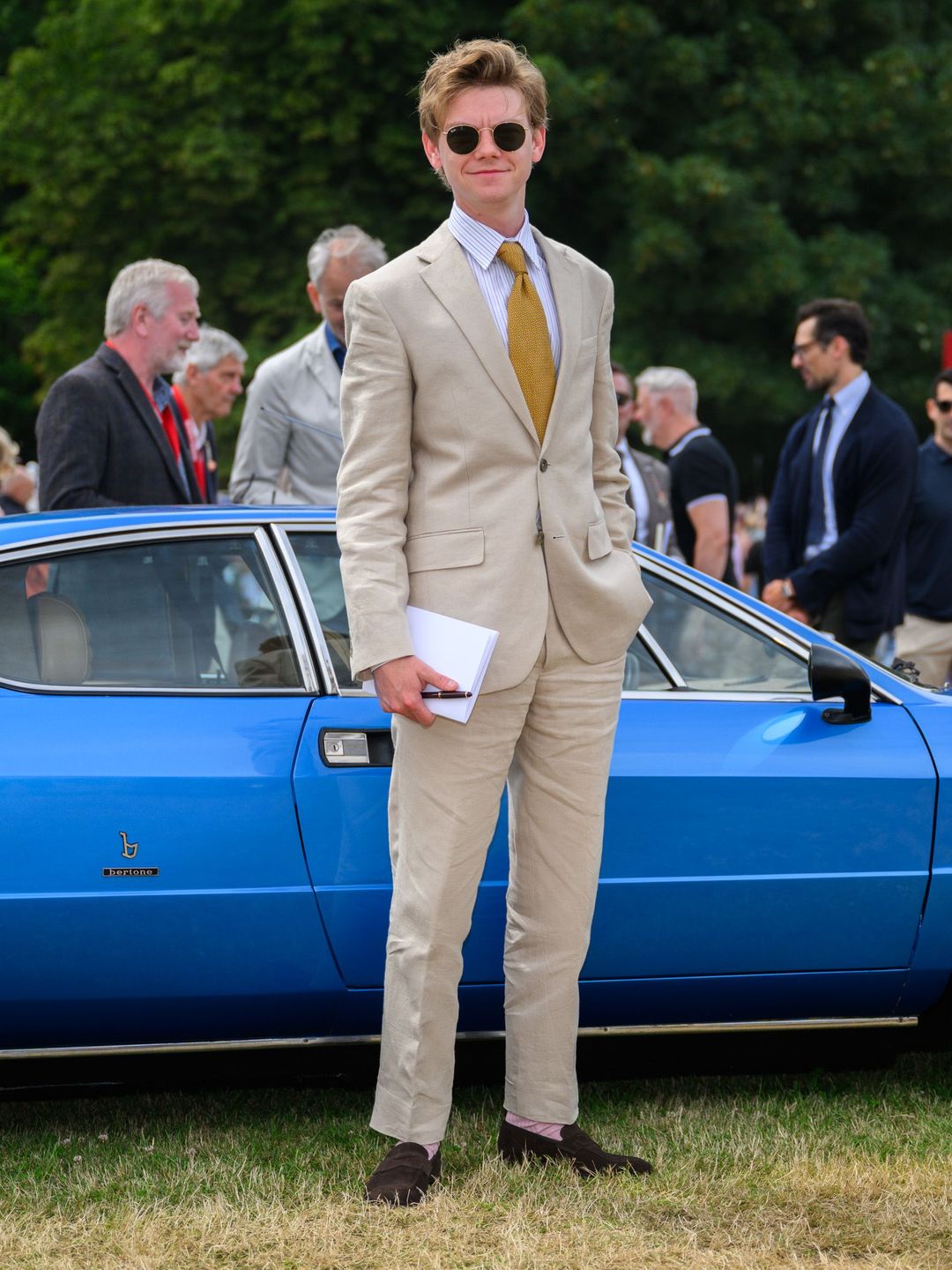 man in suit posing in front of classic car