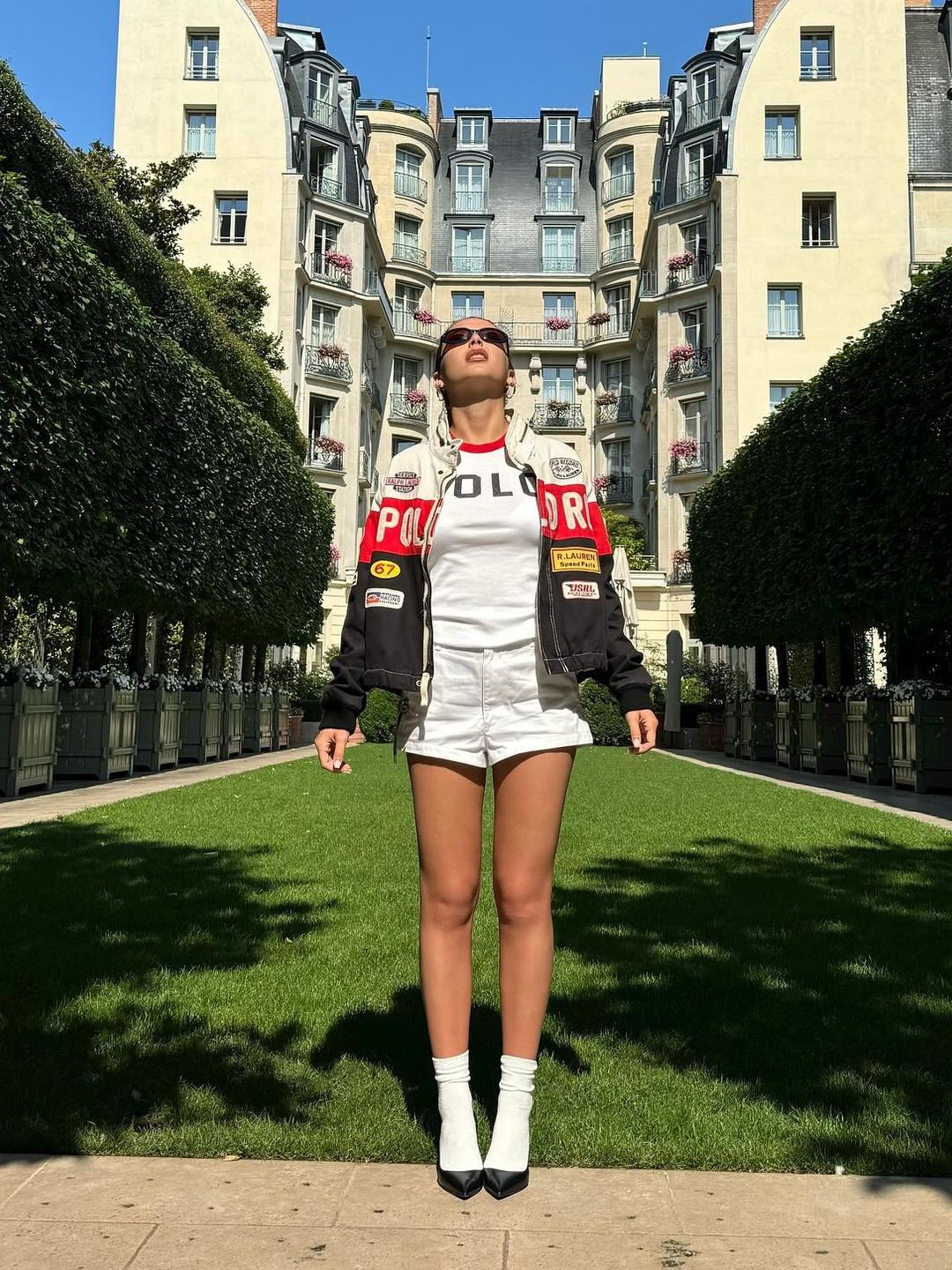 Emma Chamberlain poses in white shorts and a motorcycle jacket at the Olympic Games