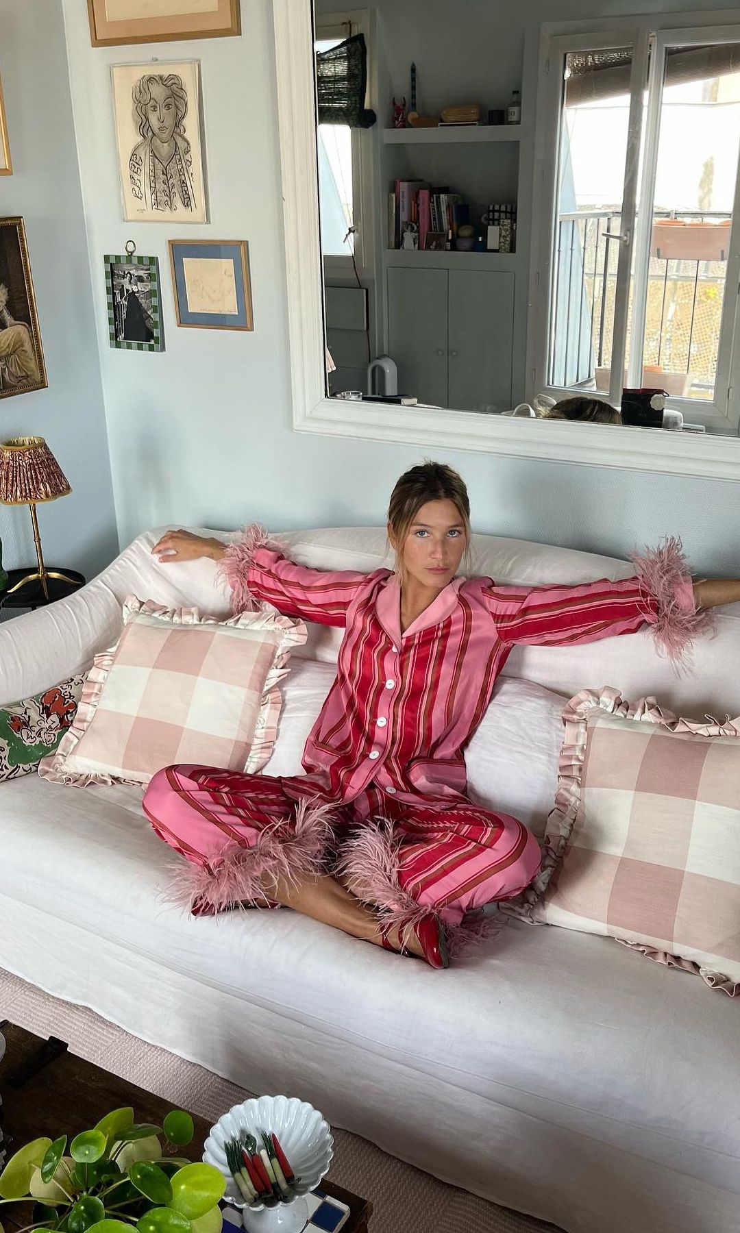 A girl sits on her couch in striped pyjamas 