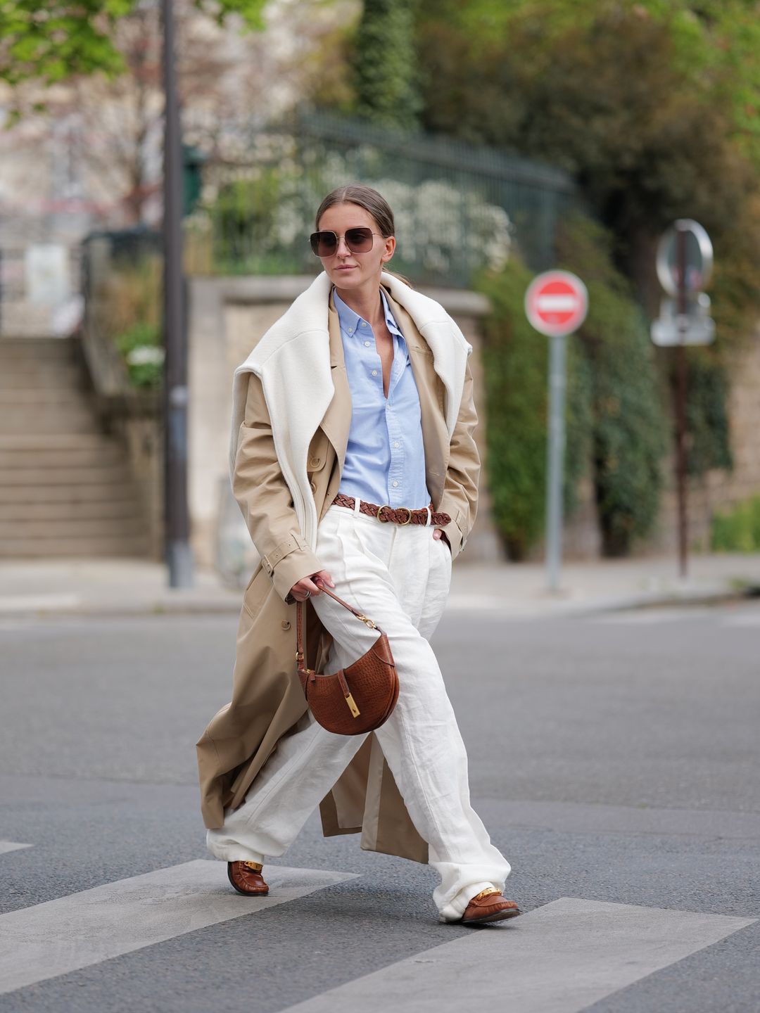 Woman wearing a trench coat with white trousers 