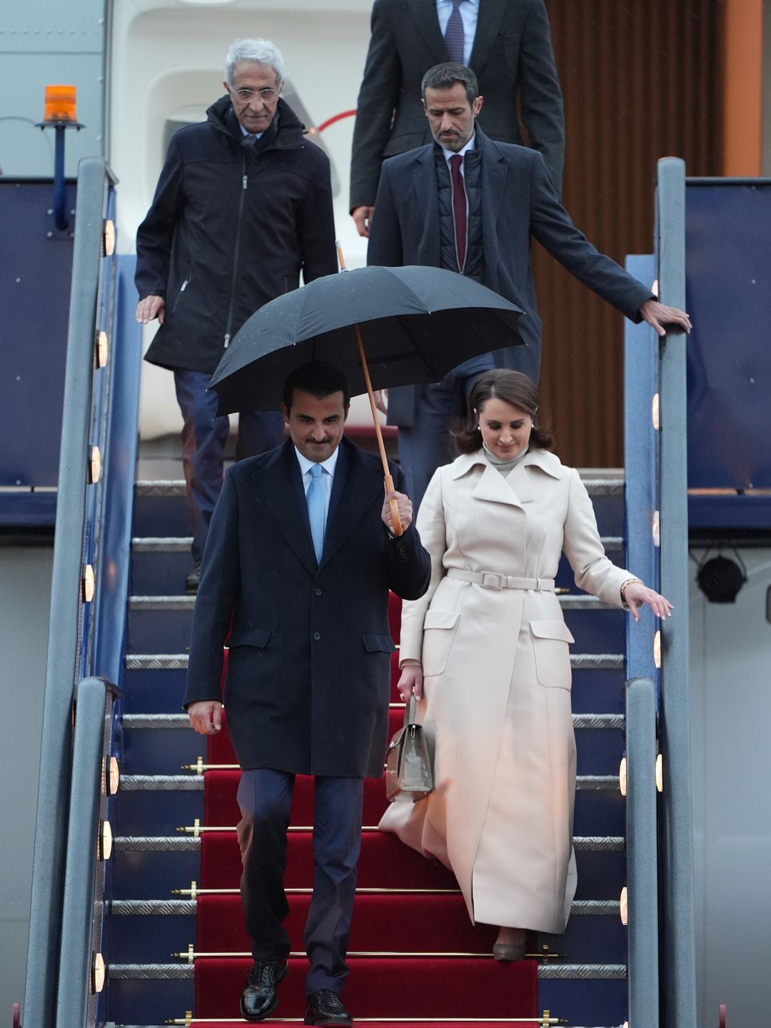 emir of qatar and wife getting off plane at airport 