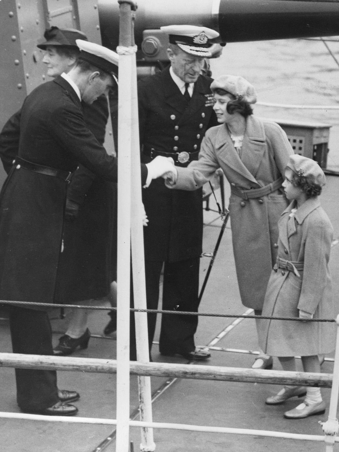 Young Queen Elizabeth and Princess Margaret shaking hands with naval personnel