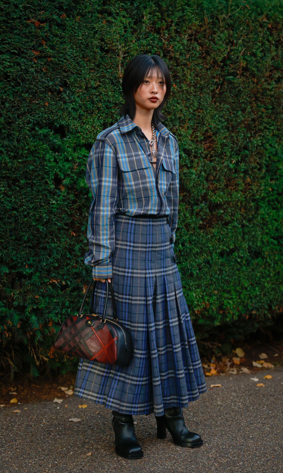  guest wearing blue Burberry check shirt, matching maxi skirt, black boots and Burberry red check bag outside Burberry during London Fashion Week