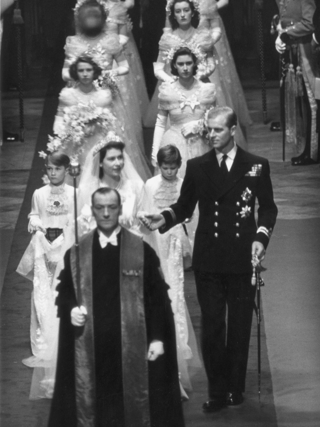 The Queen and Prince Philip walking down Westminster Abbey behind the Archbishop of Canterbury - bridesmaids follow the pair