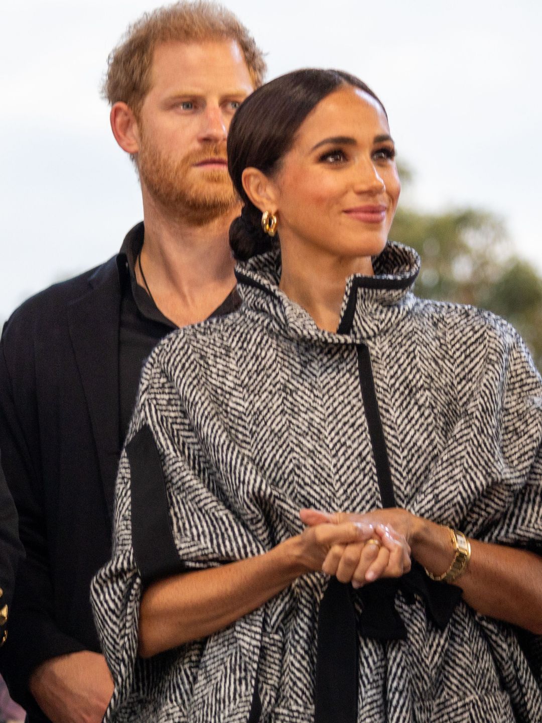 Meghan Markle smiling in a wooly poncho