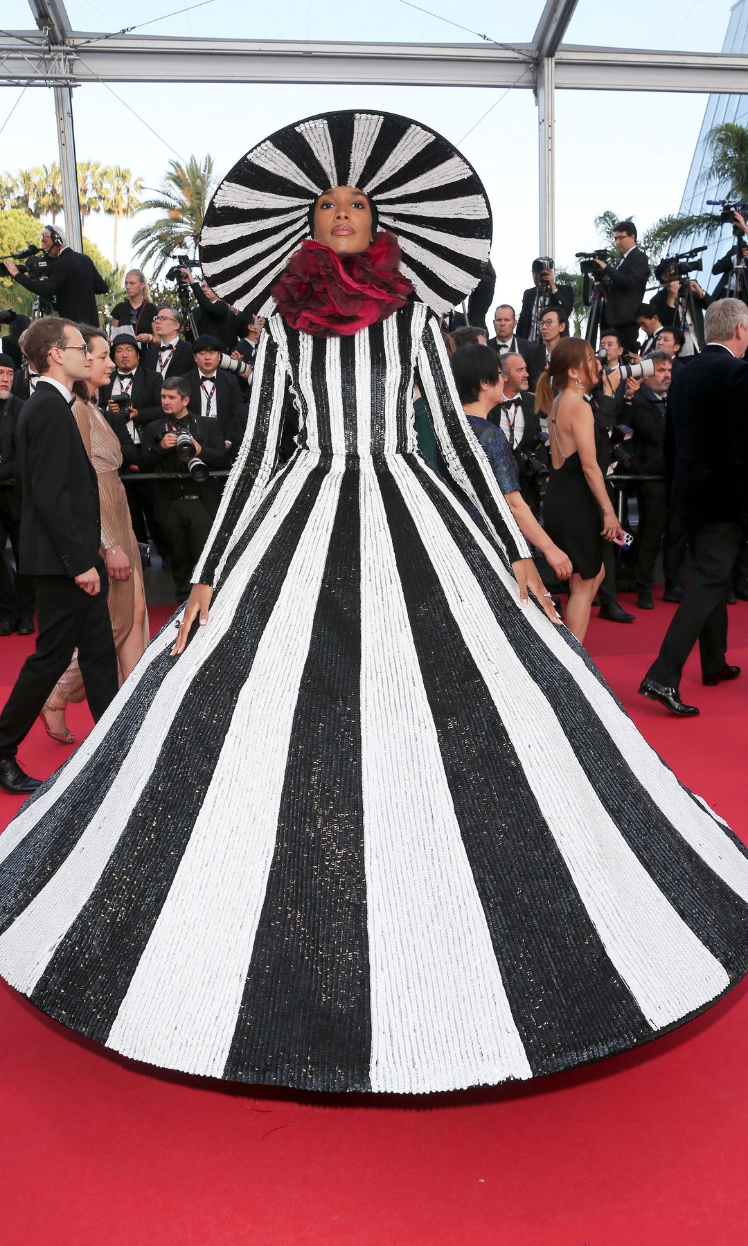 Ikram Abdi attends the "Elemental" screening and closing ceremony red carpet during the 76th annual Cannes film festival at Palais des Festivals on May 27, 2023 in Cannes in a stripe structured gown and hat