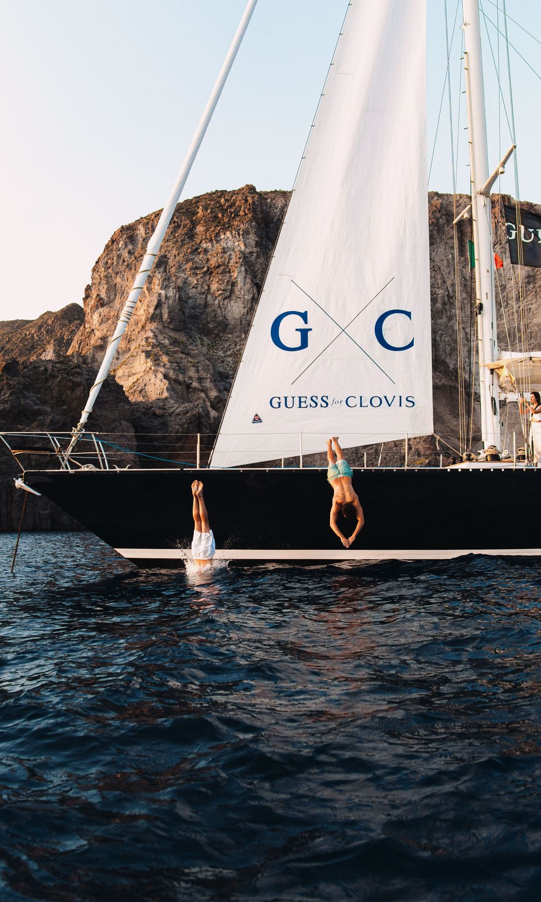 Two people jump off of the GUESS for Clovis yacht into the sea