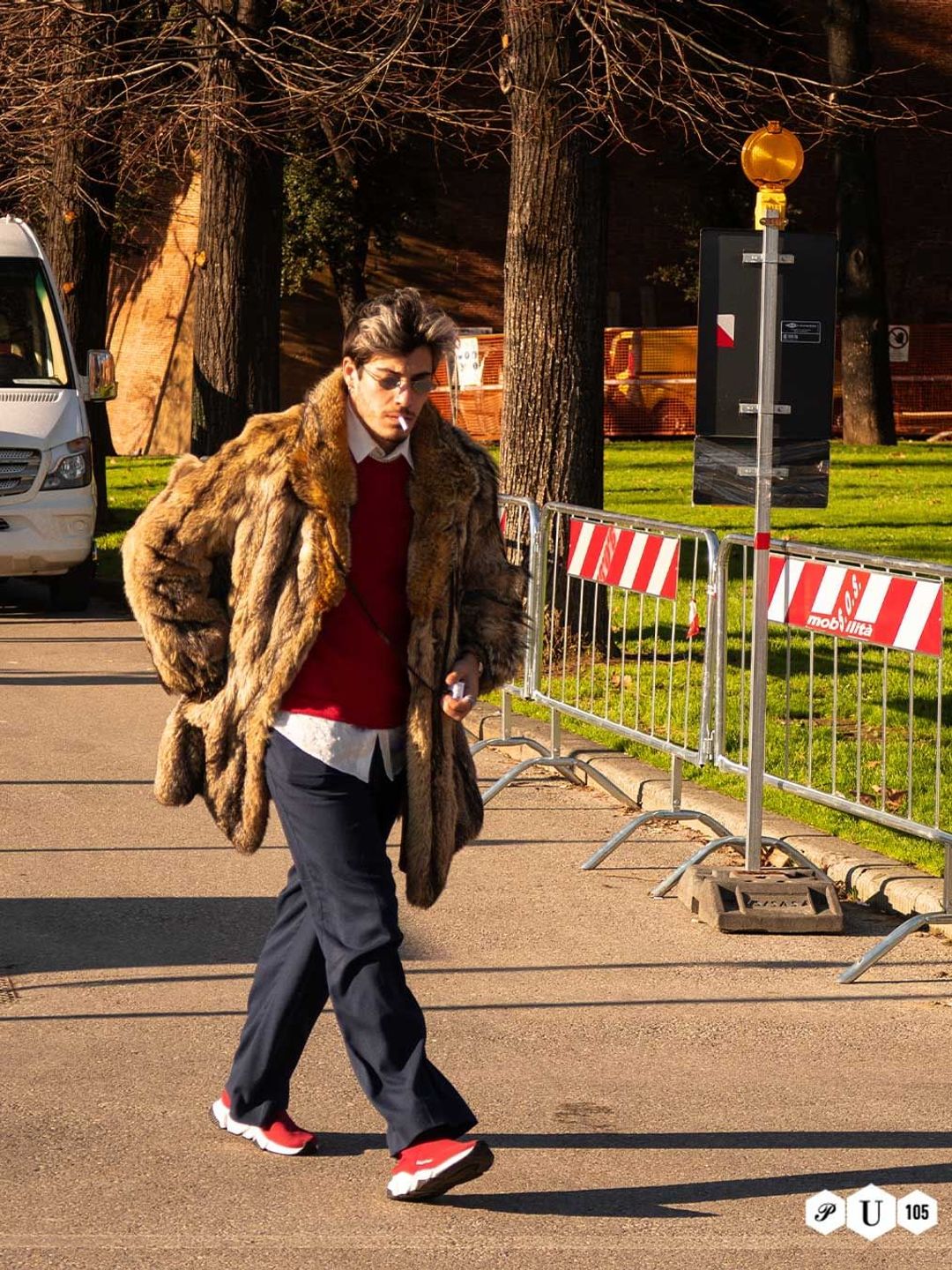 A guest arrives at Pitti Uomo in Florence wearing a fur coat and red jumper