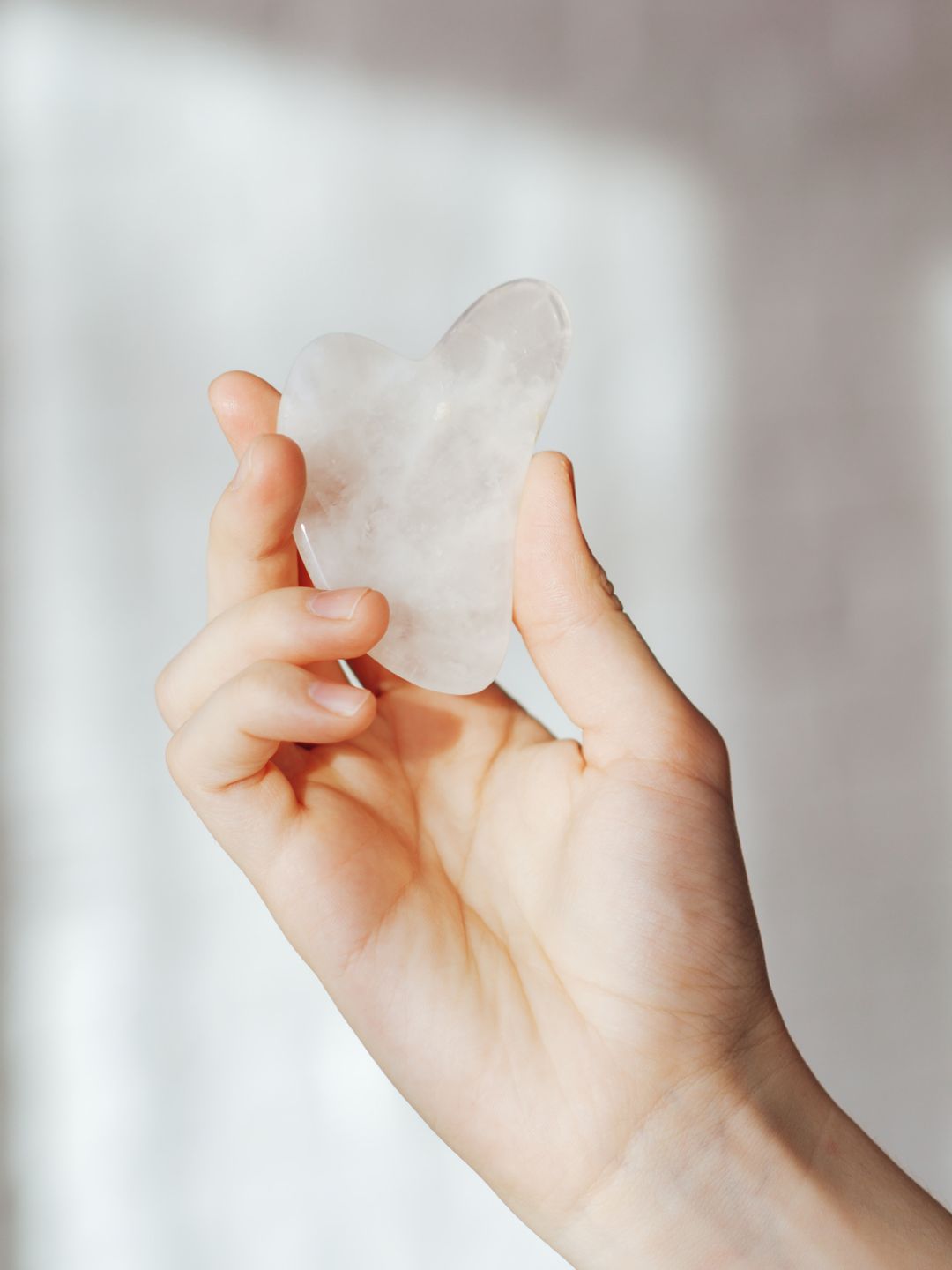 Hand holding stone massager against light background