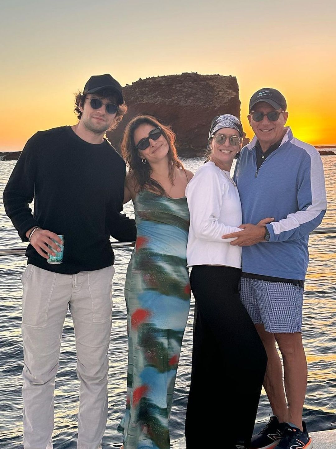 The blended family stood smiling wearing sunglasses on a beach at sunrise