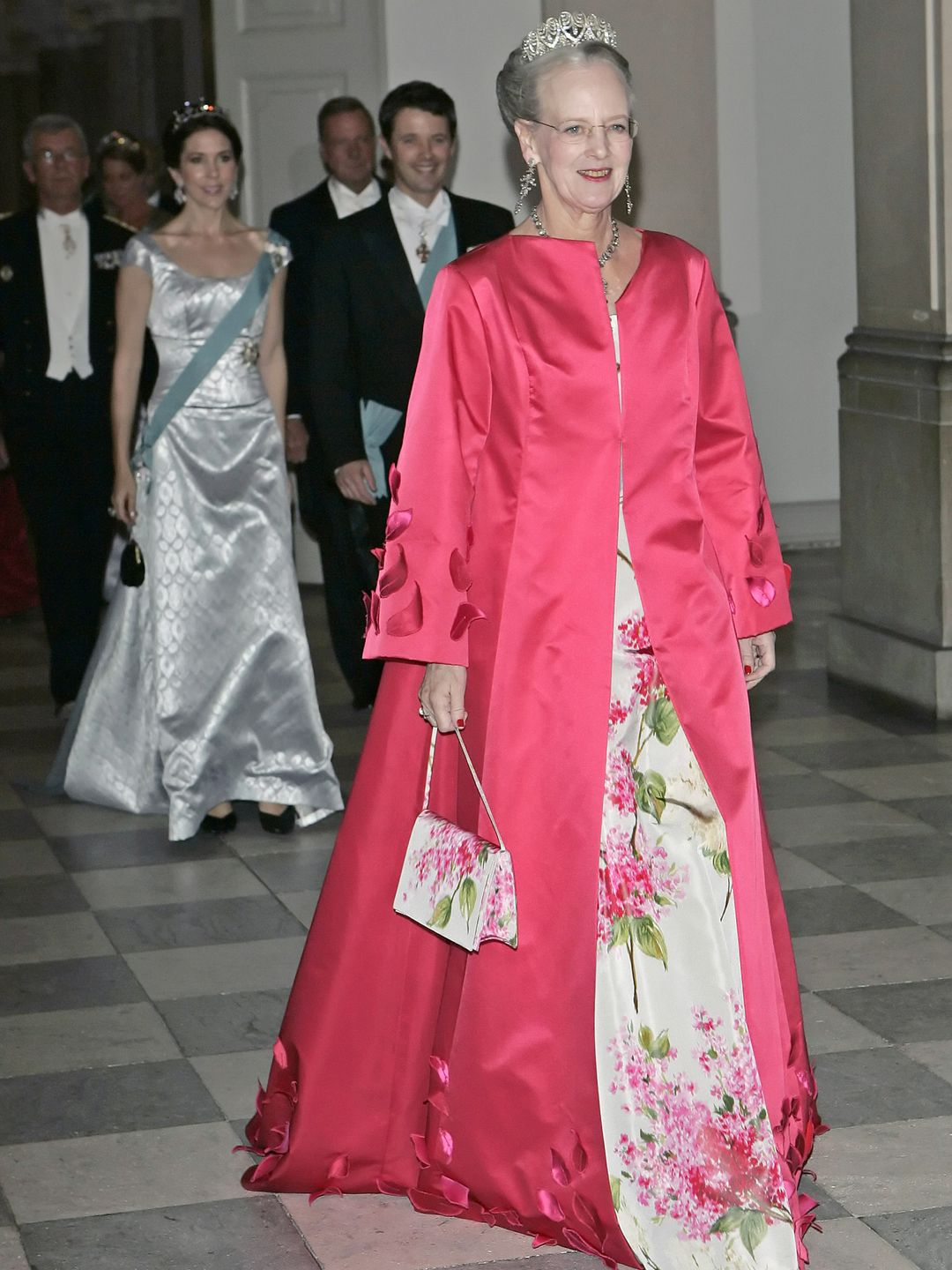 Queen Margrethe attends her sons wedding wearing a floral gown and bright pink overcoat 