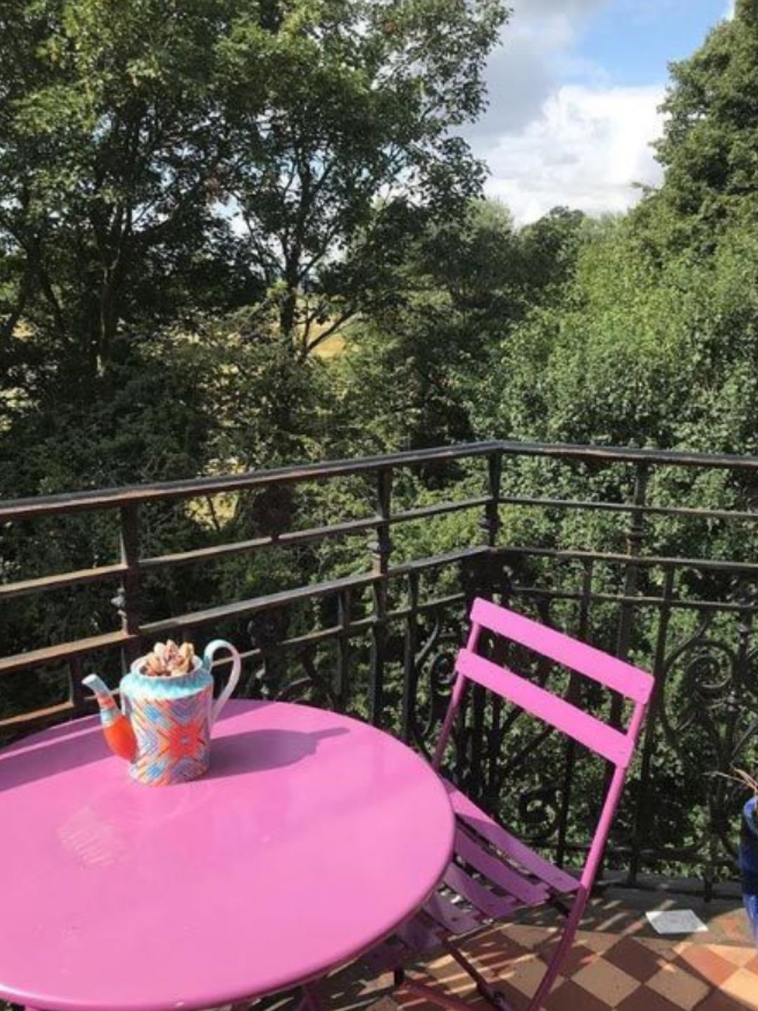 A pink chair and table on a balcony