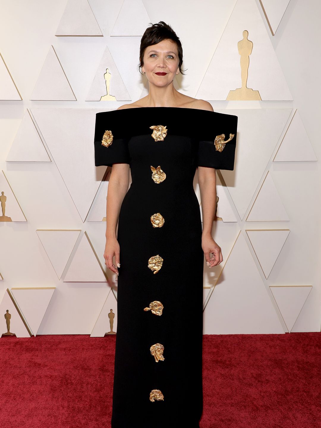 Maggie Gyllenhaal attends the 94th Annual Academy Awards in an off-the-shoulder black gown with gold accents