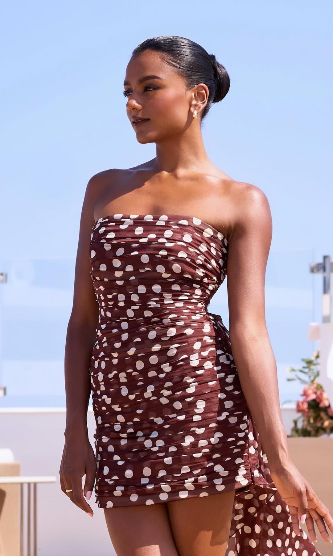 Simone Ashley poses in a brown polka dot mini dress