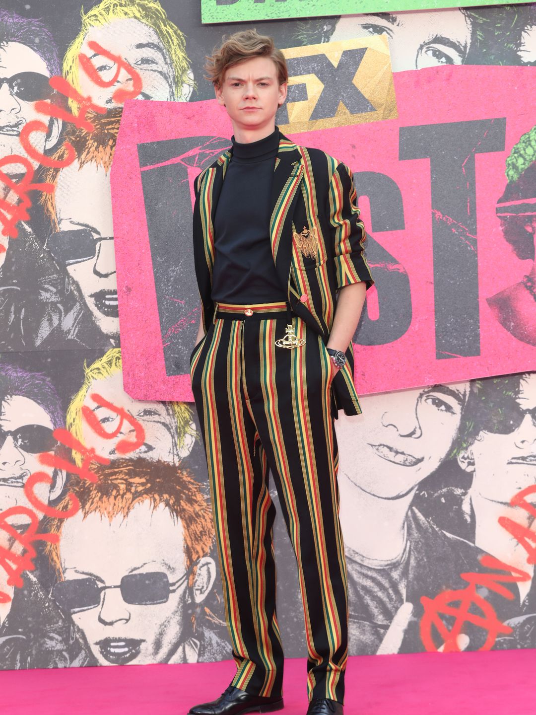 actor posing on pink carpet in striped suit