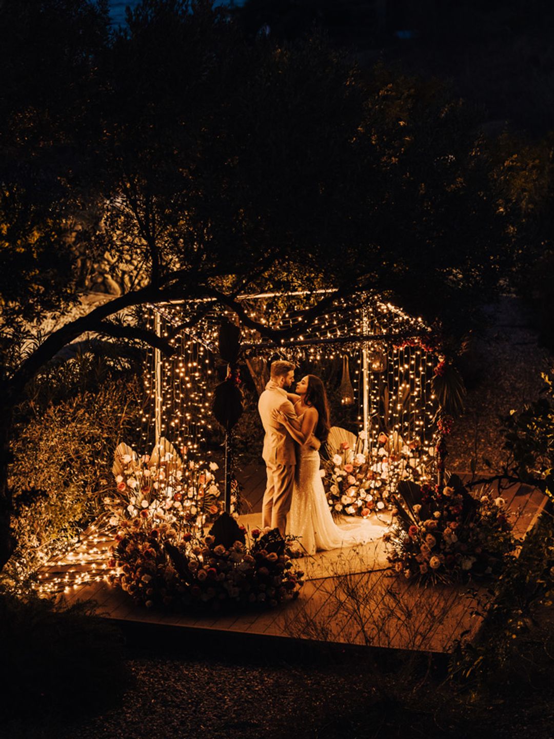 Bride and groom dancing underneath fairylights at night