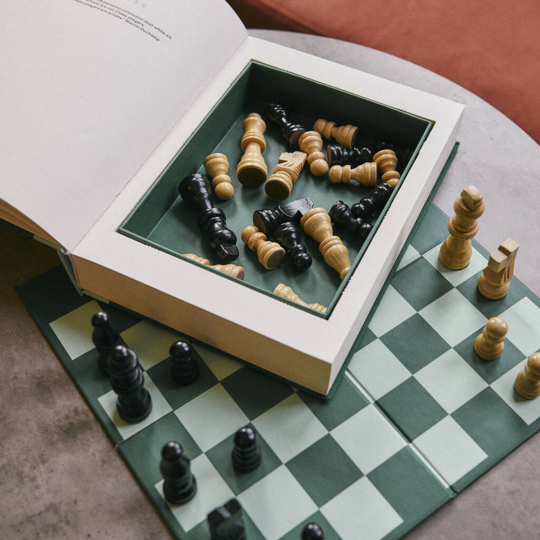 A green chess set photographed on a marble table 