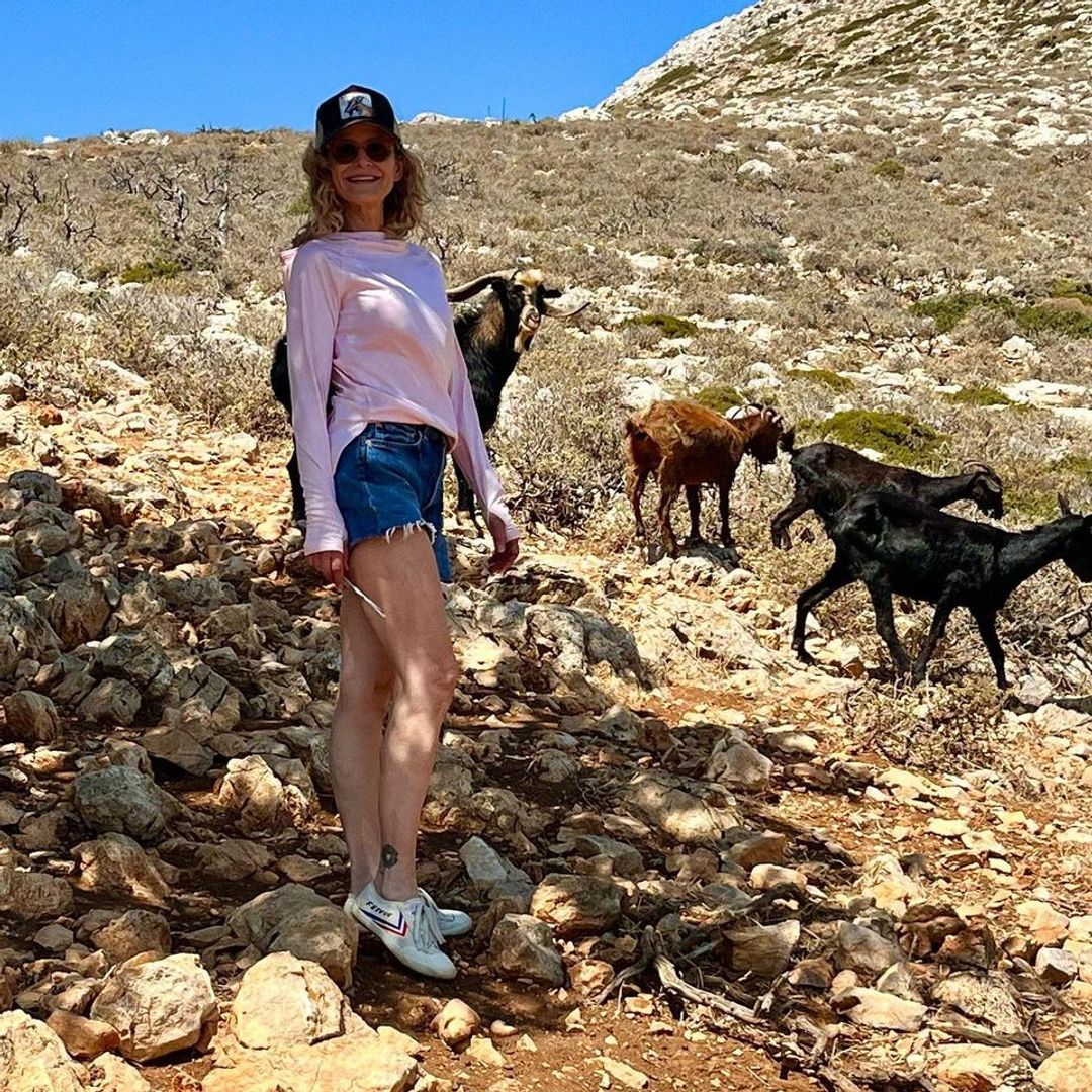 Kyra Sedgwick poses near some goats