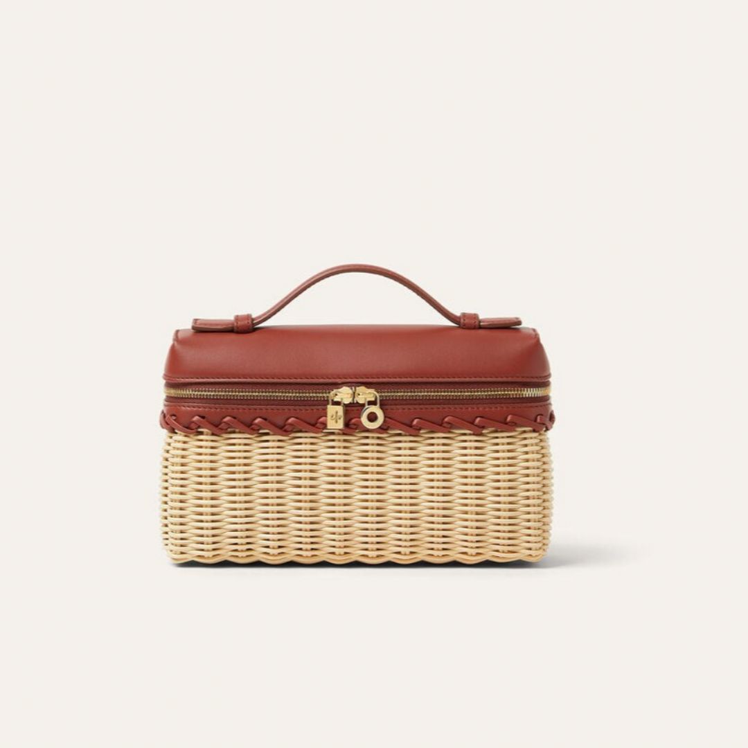 Close-up of a small structured handbag featuring a woven wicker base, tan leather top, gold zipper closure, and a curved leather handle, blending rustic charm with luxury craftsmanship for a timeless, quiet luxury accessory.