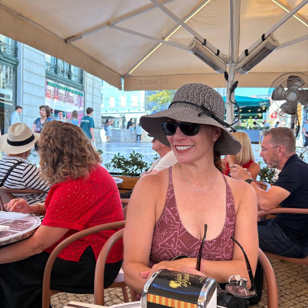 A woman in a hat sits under a sunshade in Lisbon