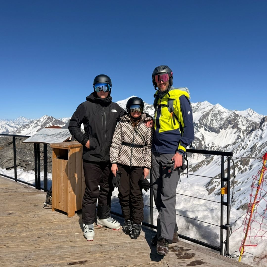 Three people posing in front of snowy mountains