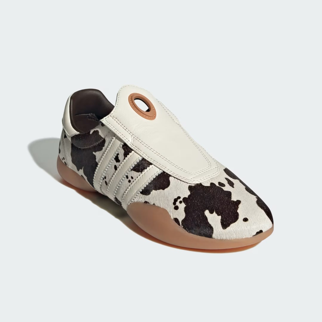 A photo of a singular Adidas Taekwondo Mei Shoes in cowprint on a white background 