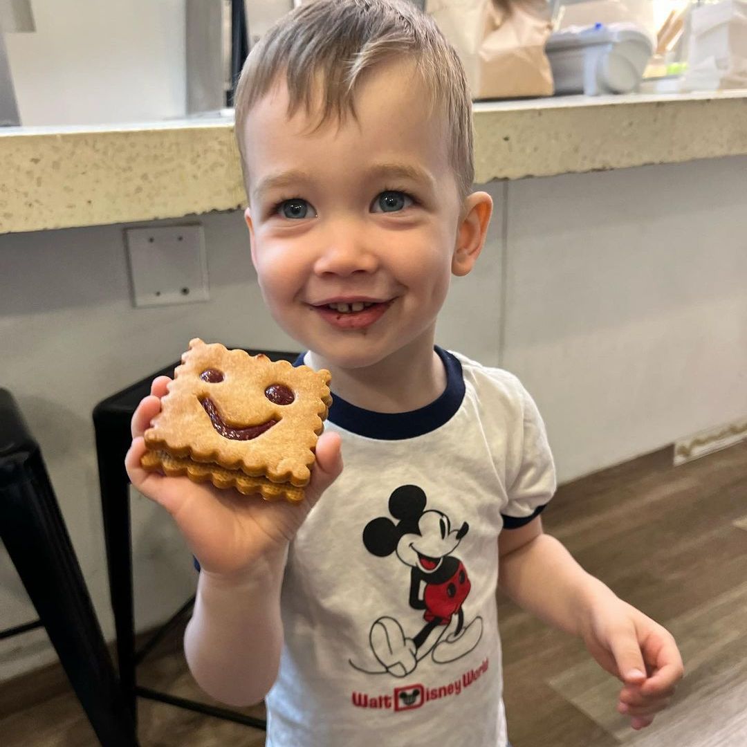 Wyatt smiling while stood in a kitchen holding a cookie