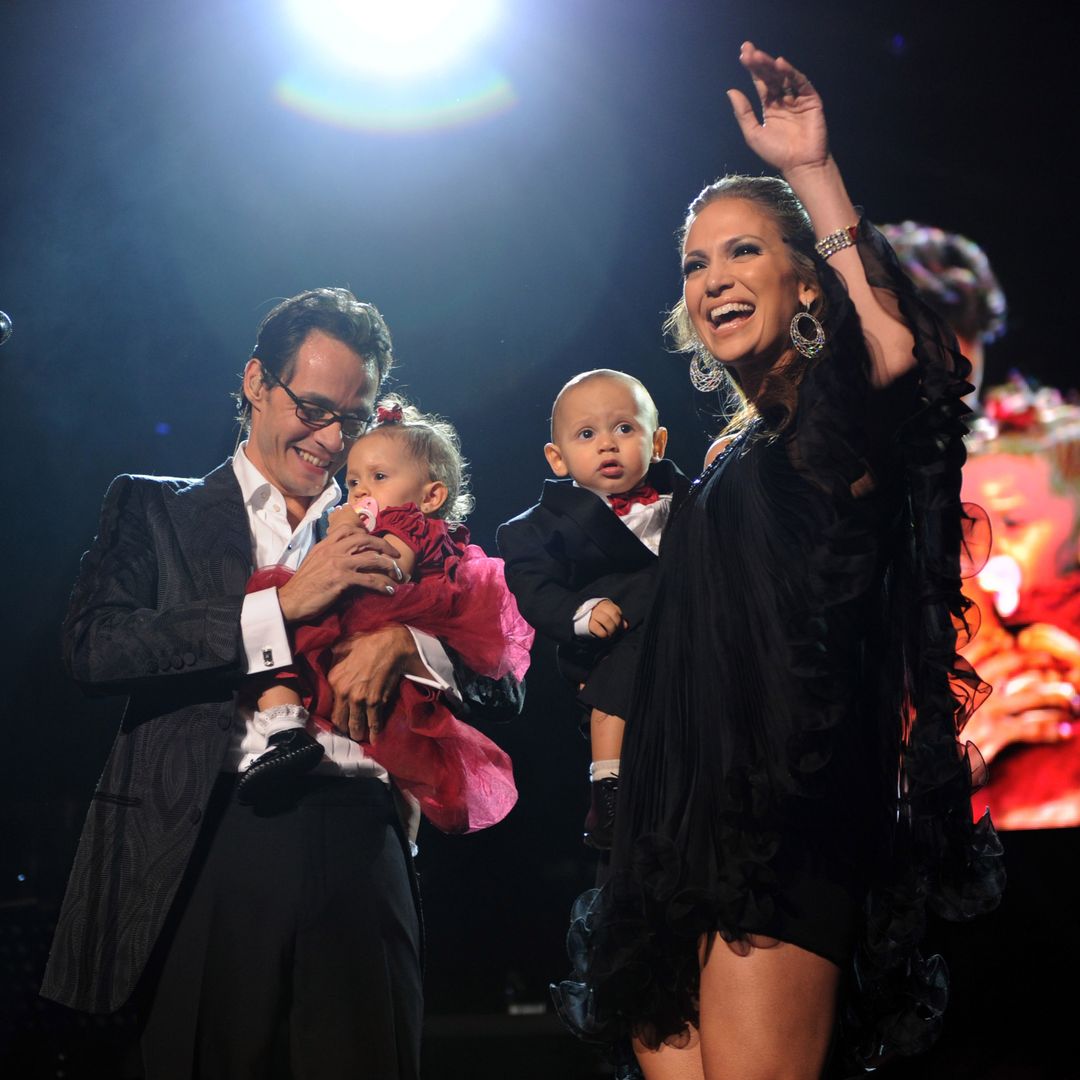 Jennifer Lopez and Marc Anthony on stage waving and holding their twins