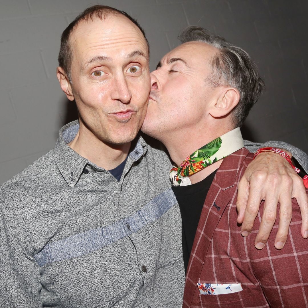 Alan Cumming kissing husband Grant Shaffer on the cheek