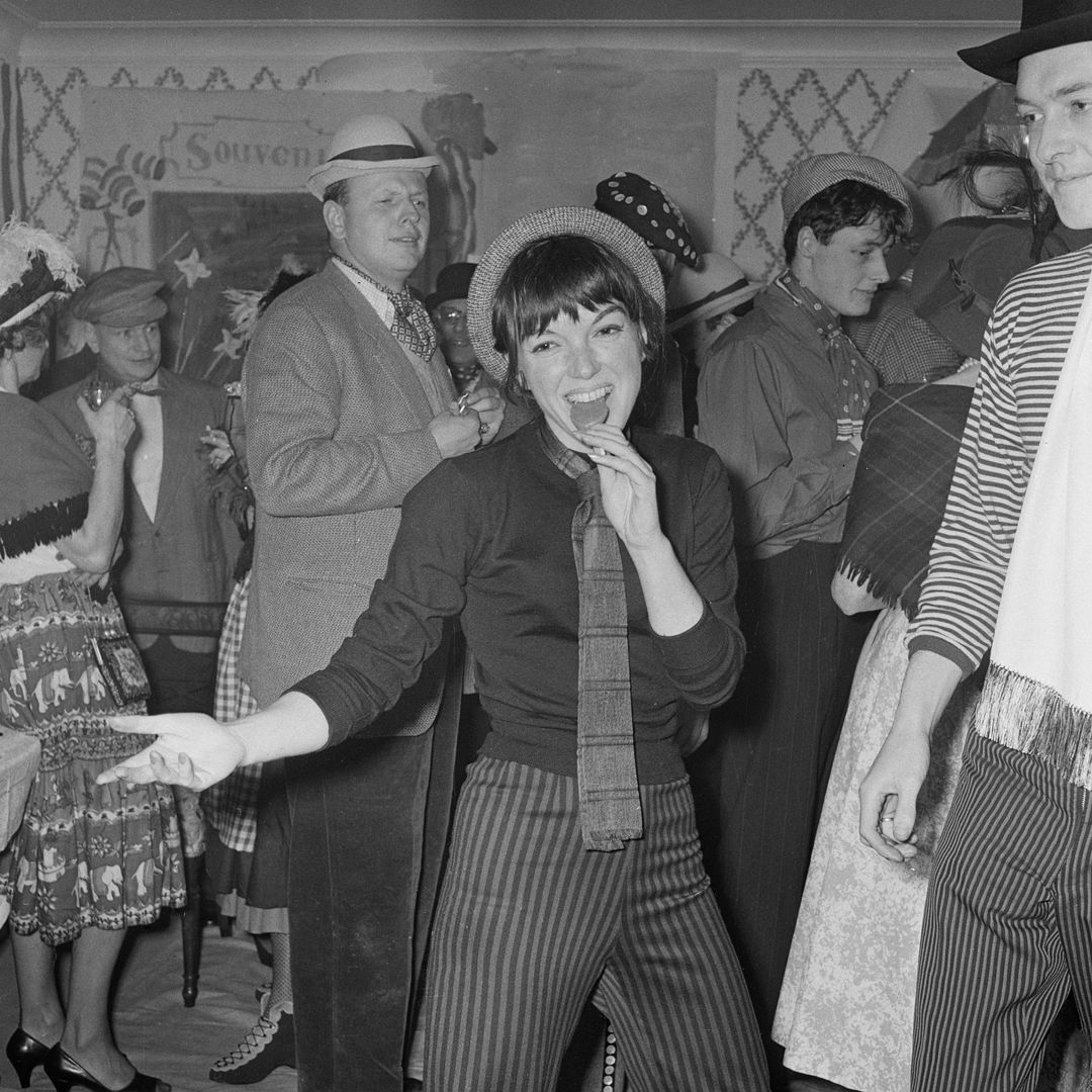 English fashion designer Mary Quant eating a lollipop at a party, 27th January 1959. With her is her husband, Alexander Plunket Greene (1932 - 1990, right). (Photo by Evening Standard/Hulton Archive/Getty Images)