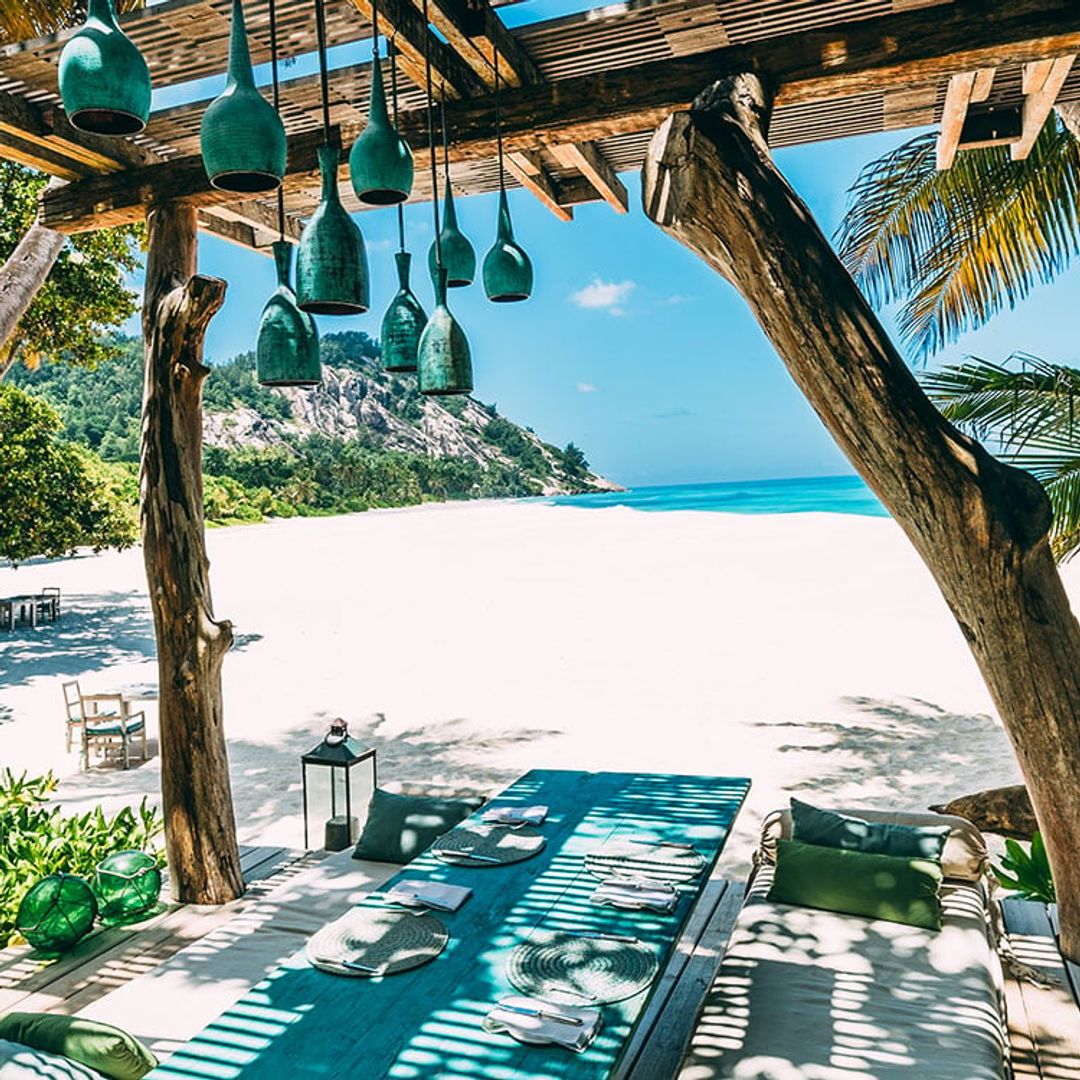 beach front with table laid out underneath pergola