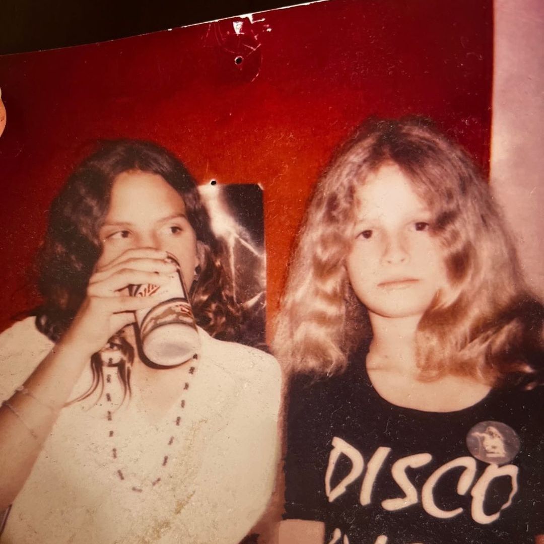 A teenage Kyra sat with a friend in an old photograph
