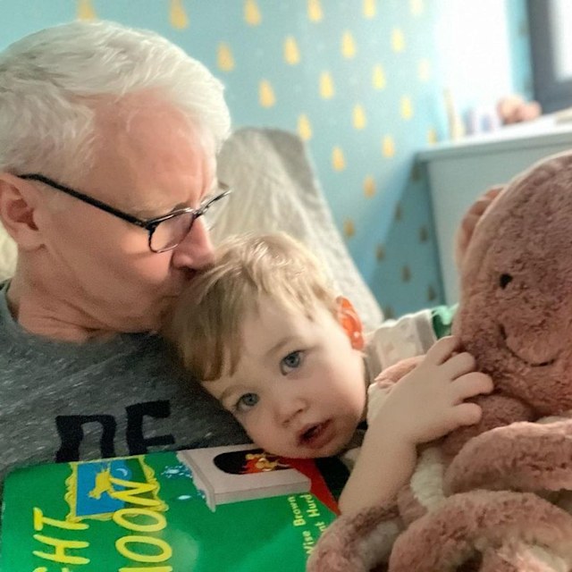 Anderson reading to Wyatt, who is cradling a large Octopus plush