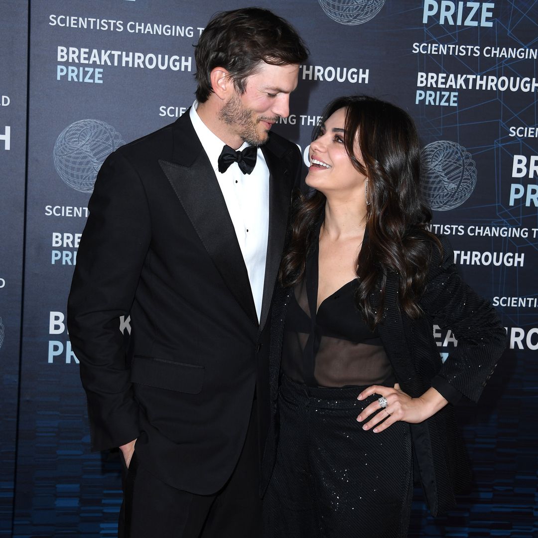 Ashton Kutcher and Mila Kunis smiling at each other on a red carpet